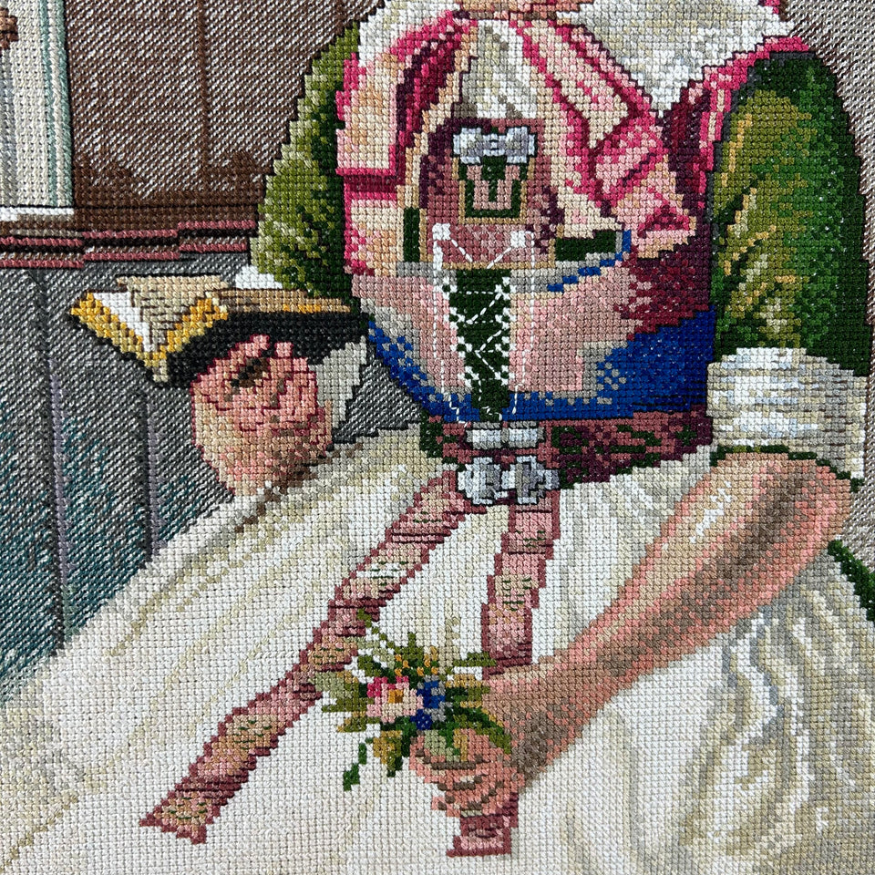 Framed needlepoint embroidery of a reading woman