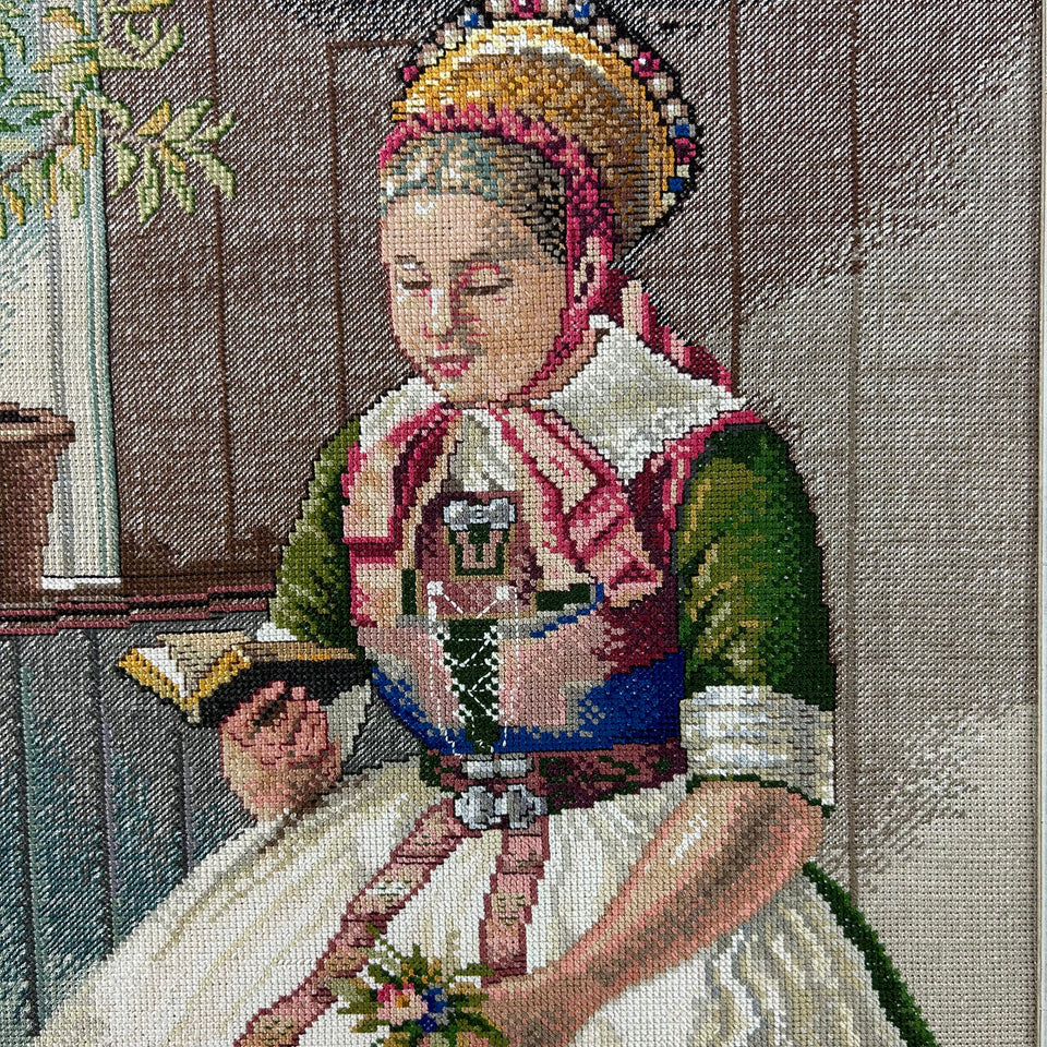 Framed needlepoint embroidery of a reading woman