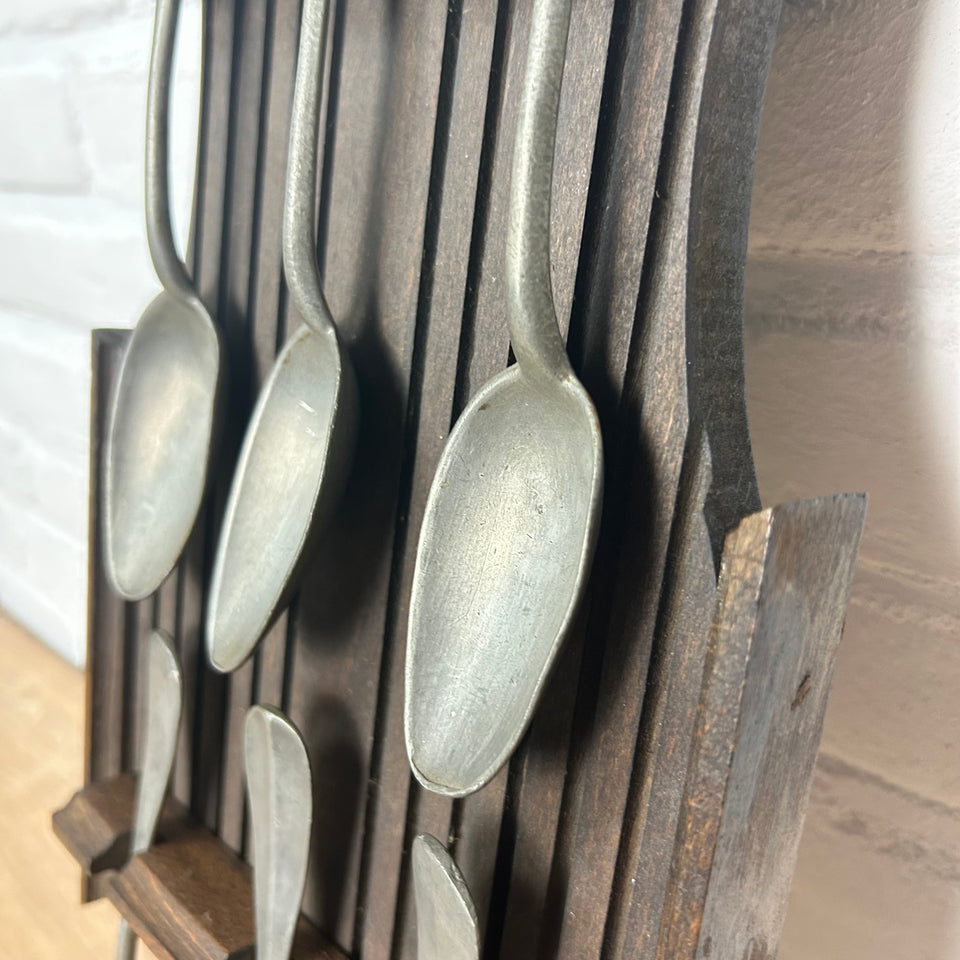Antique wooden wall display with 6 old tin spoons.