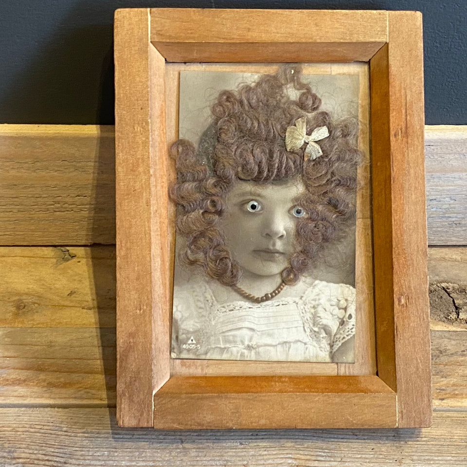 Antique (horror like) photo of a child with glass eyes and real (!) hair from 1890-1910 in wooden frame.