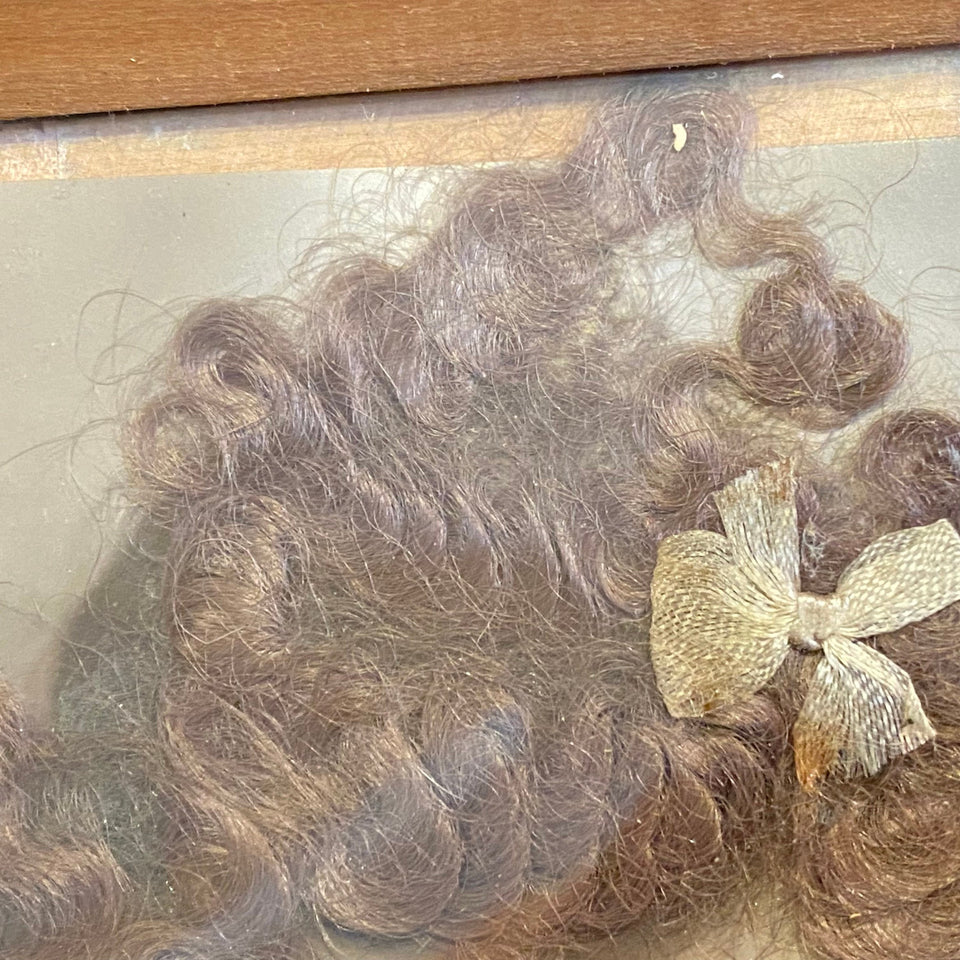 Antique (horror like) photo of a child with glass eyes and real (!) hair from 1890-1910 in wooden frame.